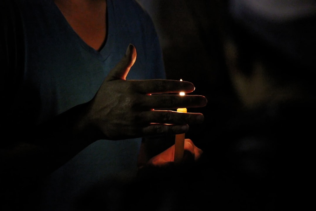 Hands holding a lit candle in darkness