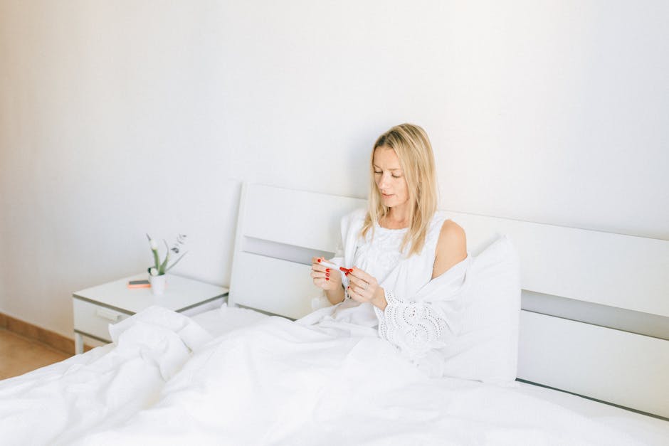 Woman sitting in bed examining a pregnancy test, conveying anticipation and hope.