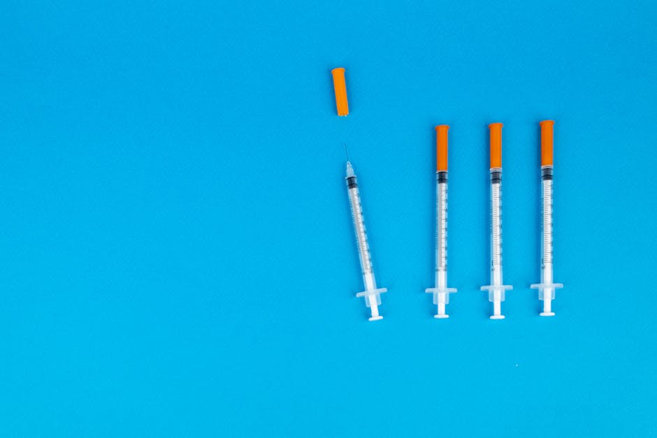 Four medical syringes with orange caps on a vivid blue background, ideal for healthcare or vaccination themes.