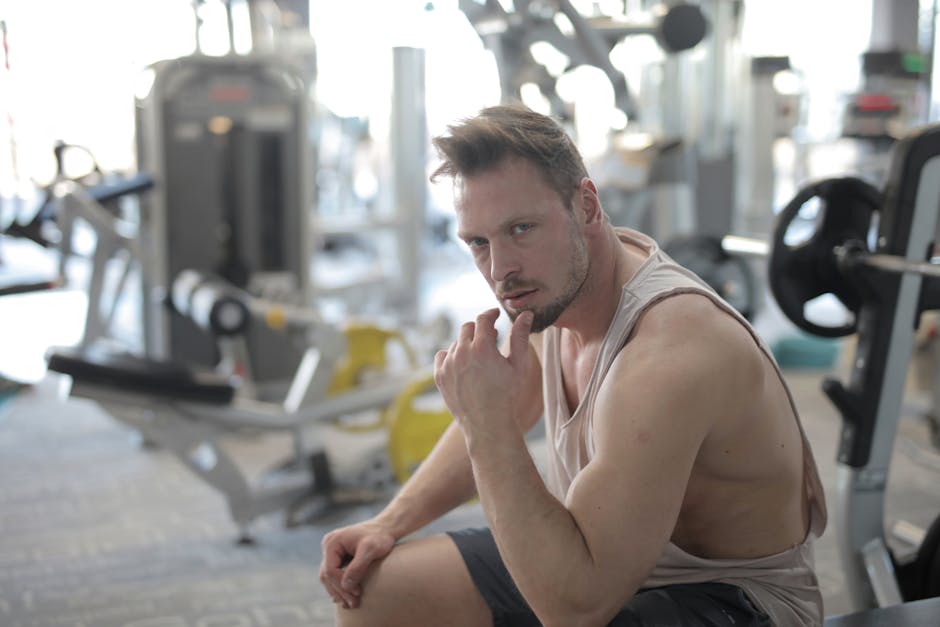 Muscular man in gym attire taking a break during an intense workout session.