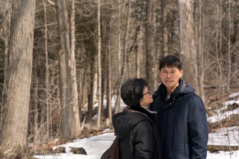 Elderly couple enjoying a peaceful winter walk in a serene forest setting.