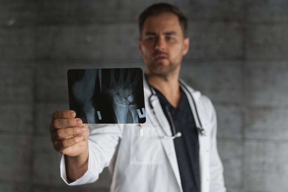 A male doctor in a lab coat holding and examining an X-ray image in a clinical setting.