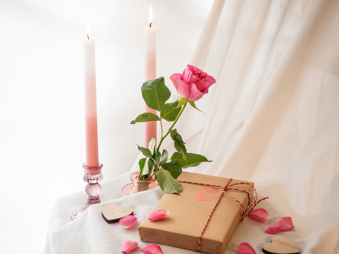 a box with a rose on a table next to two candles