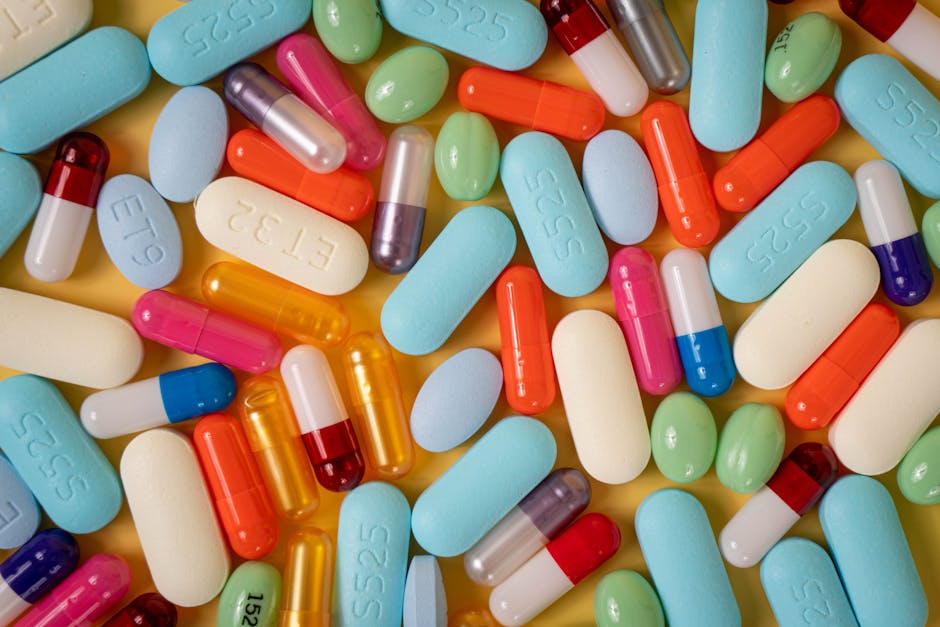 A vibrant array of various pills and capsules on a yellow background.