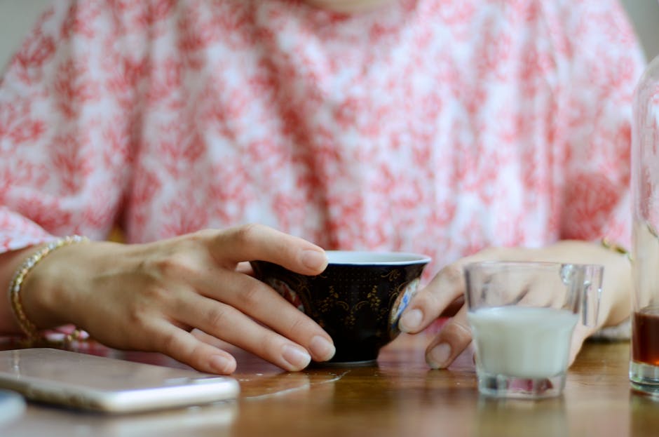Woman enjoying a relaxing morning with a hot beverage, milk, and smartphone.