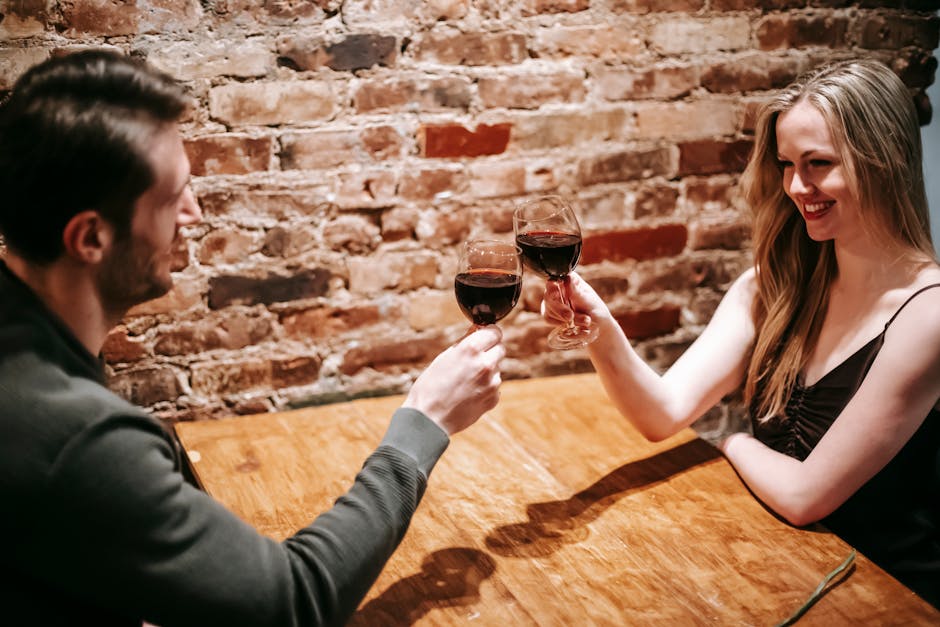 Couple enjoying a romantic evening, toasting with red wine in a cozy restaurant.