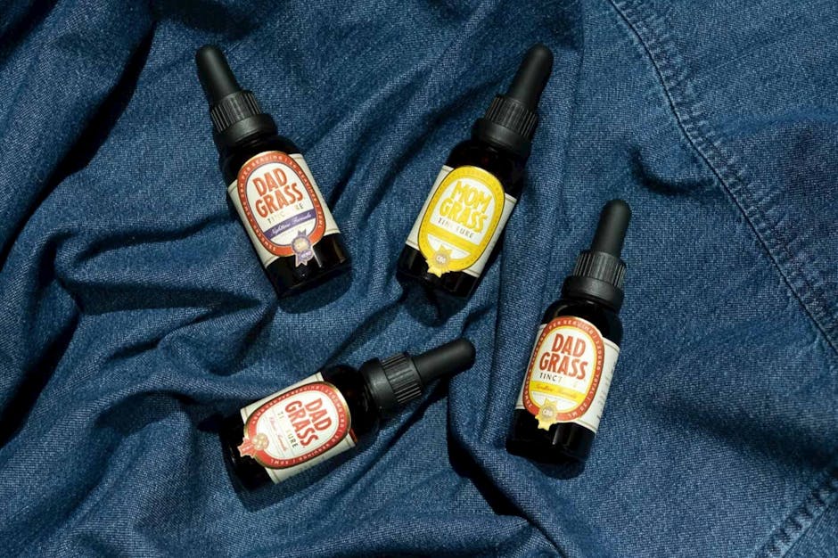 Overhead view of assorted CBD tincture bottles on blue denim fabric.