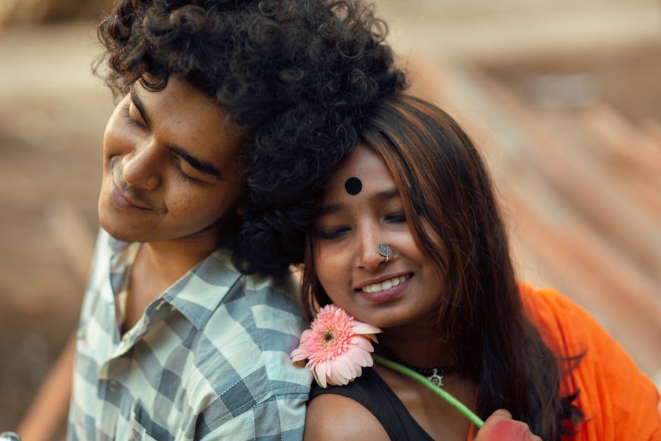 Young couple sitting back to back sharing a tender moment with a flower.