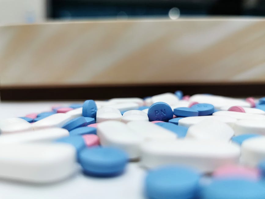Close-up image of assorted blue and white pills scattered on a table, indoors.