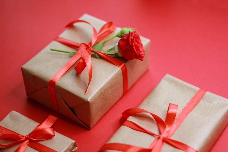 Beautifully wrapped gift boxes with red ribbons and a rose on a vibrant red background.
