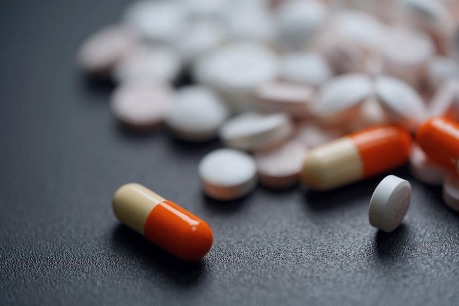 Assorted pills and capsules on a dark background, emphasizing medication variety.